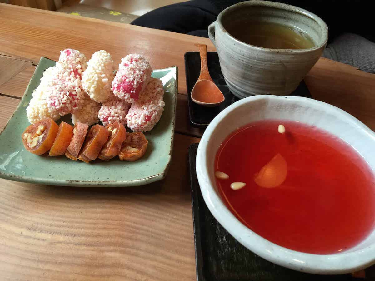A cup of Omija tea with traditional Korean snacks next to it.