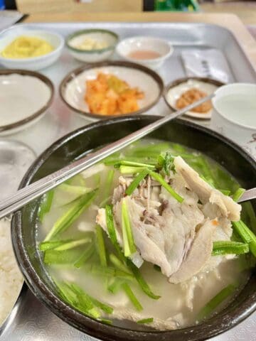 A bowl of Gukbap Korean Pork Rice Soup, with side dishes.